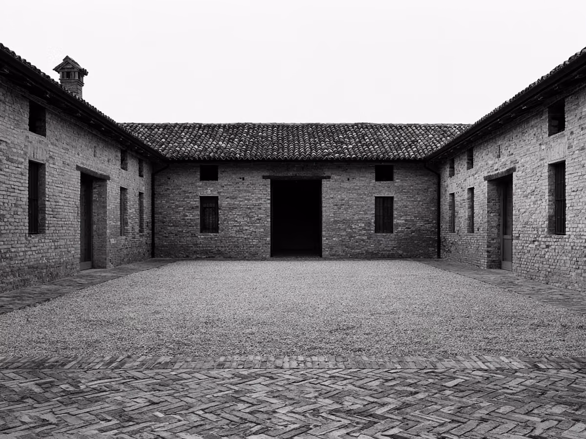 Corte agricola in mattoni a vista ripresa frontalmente, con il nuovo tetto in coppi sui tre lati e il passaggio centrale del fienile